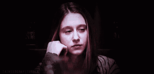 a woman is touching her hair in a dark room .