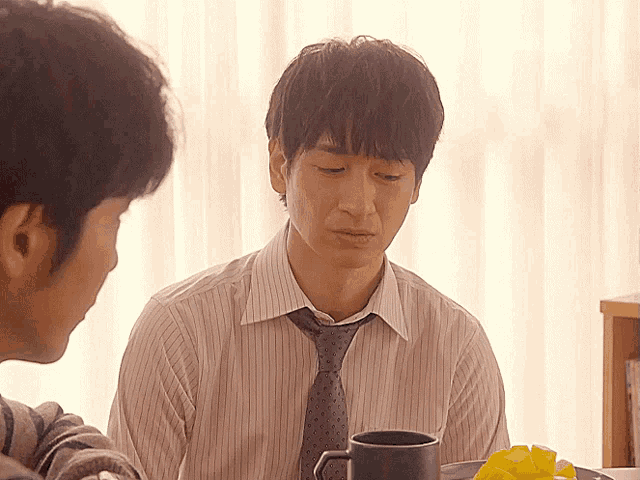 a man in a striped shirt and tie looks down at something