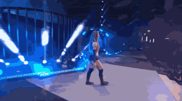 a woman is walking down a stage with blue lights