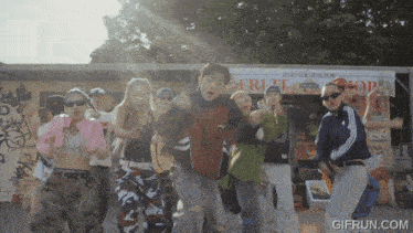 a group of people are dancing in front of a fruit stand that says fruit