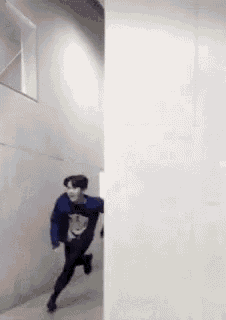 a man in a blue sweater is running through a hallway .