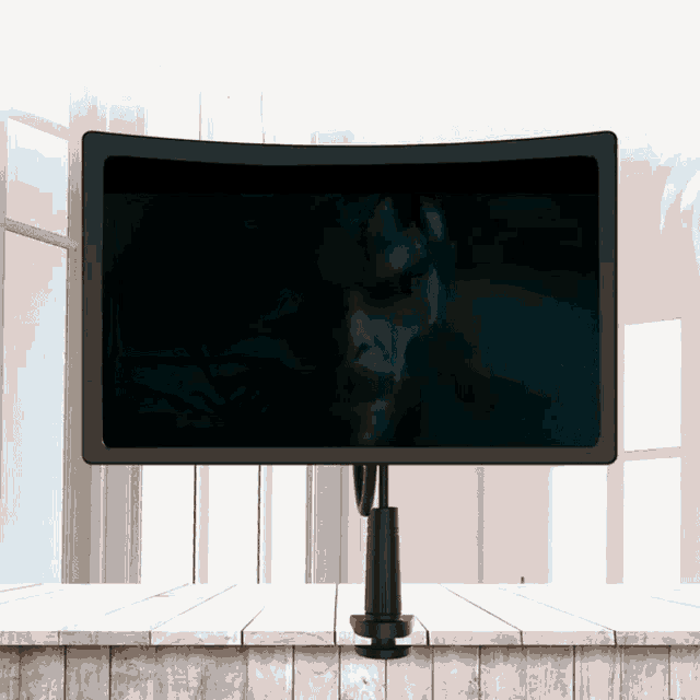 a curved monitor shows a man 's face in a dark room