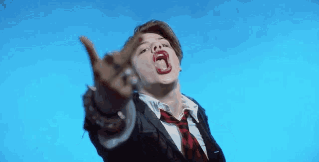 a man in a suit and tie is making a funny face with his mouth open and pointing .