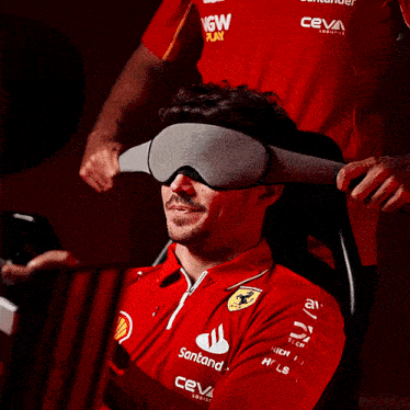 a man wearing a red shirt that says santander is smiling
