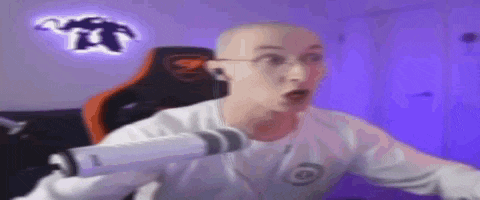a bald man is sitting in a chair in front of a microphone in a room .