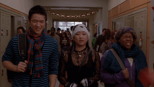 a group of people walking down a hallway with lockers and a star on the wall