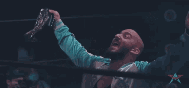 a man in a wrestling ring holds up his arms in the air with a star in the background