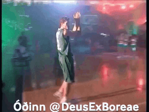 a man in a green jersey stands on a basketball court with the words odinn @deusexboreae above him