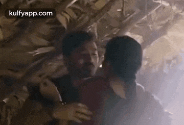 a man and a woman hugging each other in a dark room .