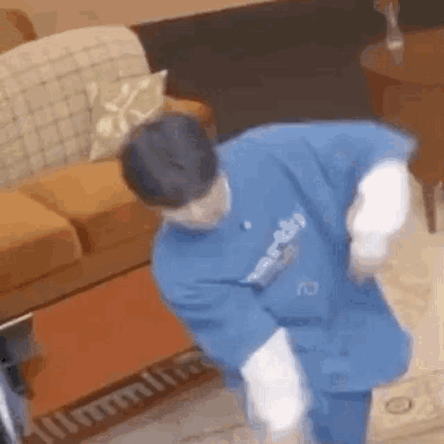a man in a blue shirt is standing in a living room .
