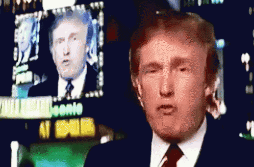 a man in a suit and tie stands in front of a sign that says ' donald trump '