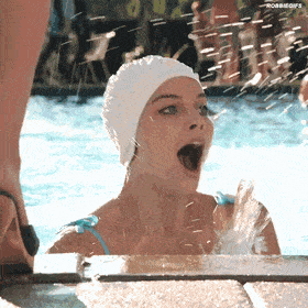 a woman wearing a swim cap is splashing water in a swimming pool
