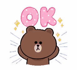 a brown bear is holding his hands up in the air while a pink sticker with the word ok on it .