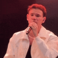 a man singing into a microphone with red hair