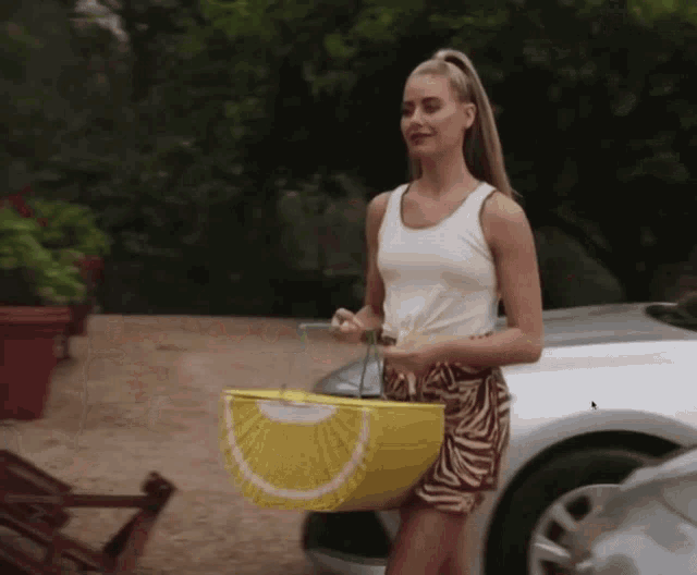a woman in a white tank top is holding a lemon shaped basket