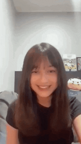 a young girl with long hair is smiling and looking at the camera .
