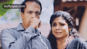 a man and a woman are standing next to each other and the man is covering his nose .