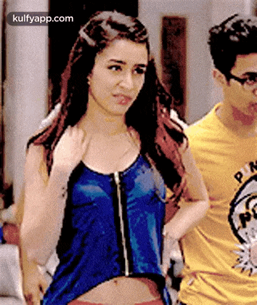 a woman in a blue tank top and a man in a yellow shirt are standing next to each other .