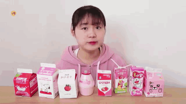 a girl is standing in front of a table full of boxes of milk including one that says ' snoopy ' on it