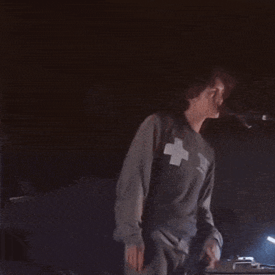 a man in a gray shirt is dancing in the dark