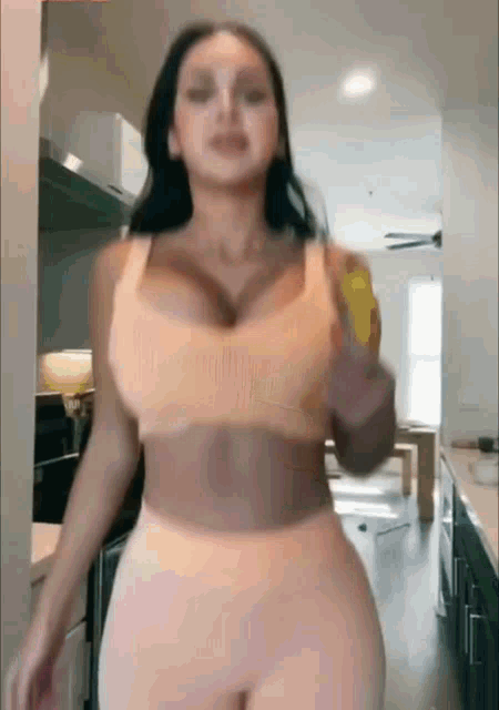 a woman is standing in a kitchen wearing a crop top and leggings .