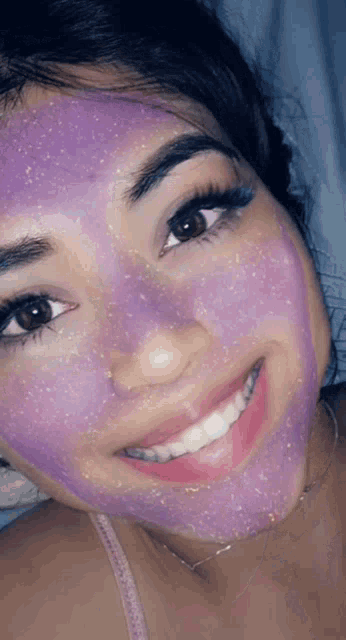 a woman wearing a purple face mask smiles for the camera