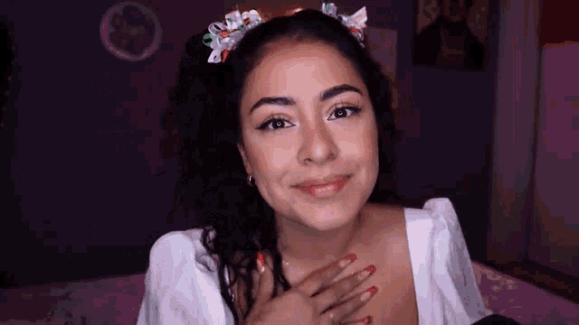 a woman wearing a headband is sitting on a bed with her hand on her chest .