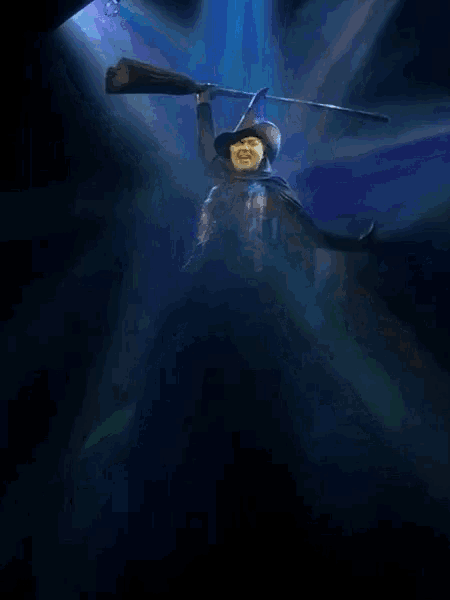 a woman in a witch costume is holding a microphone in a dark room