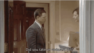 a man in a suit and tie is standing in a doorway talking to another man who is holding a box .
