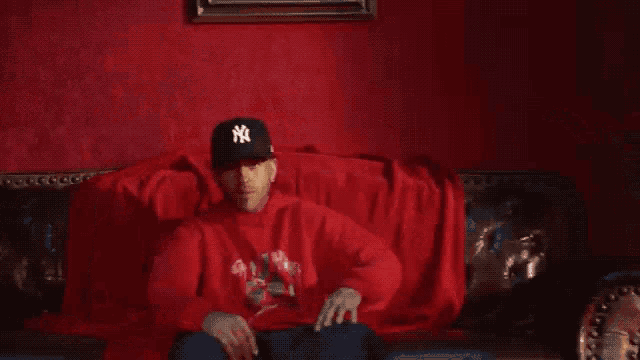 a man wearing a ny hat is laying on a couch