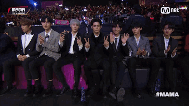 a group of young men are sitting on a couch and giving peace signs