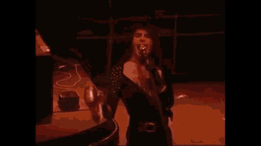 a man is singing into a microphone while playing a drum on a stage .