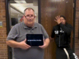 a man in a grey shirt is holding a black box that says ' i 'm sorry ' on it