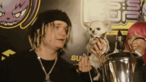 a man and a woman holding a small dog in front of a sign that says ' su ' on it
