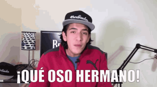 a man wearing a red jacket and a black hat says i que oso hermano