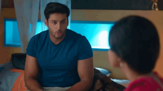 a man in a blue shirt sits next to a woman in a pink shirt