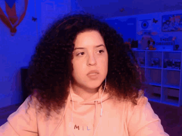 a girl with curly hair wearing a mil sweatshirt