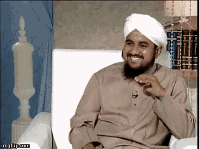 a man wearing a white turban is smiling while sitting on a chair