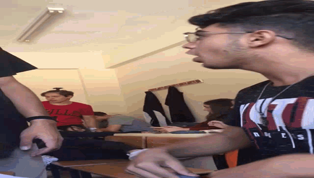 a man wearing a t-shirt that says bulls is sitting in a classroom with other students