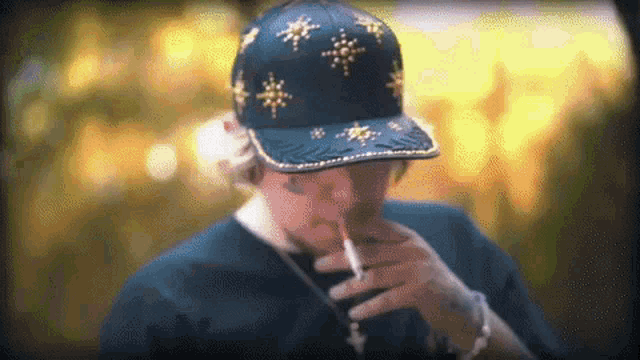 a man wearing a hat smoking a cigarette in front of a yellow background