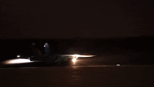 a jet is taking off from a runway at night with a bright light coming out of the tail