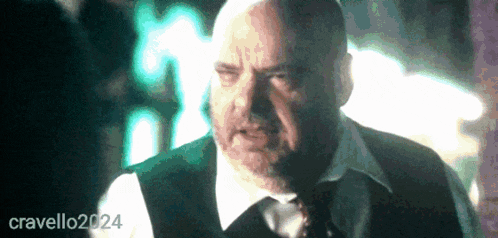 a bald man in a suit and tie is standing in front of a sign that says cravello2024