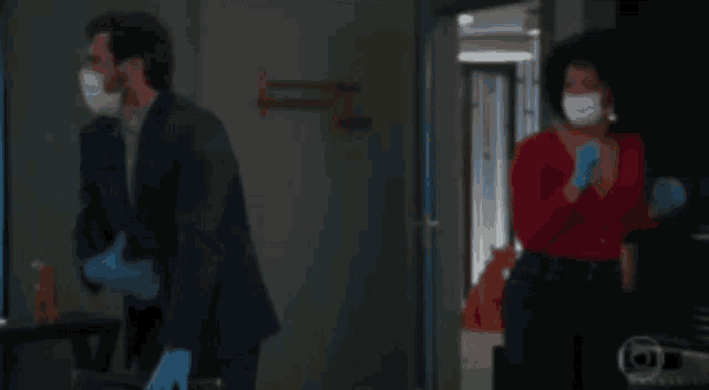 a man in a suit and a woman in a red shirt are standing in a dark room .