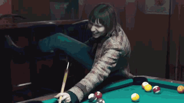 a woman is playing pool with a cue and balls