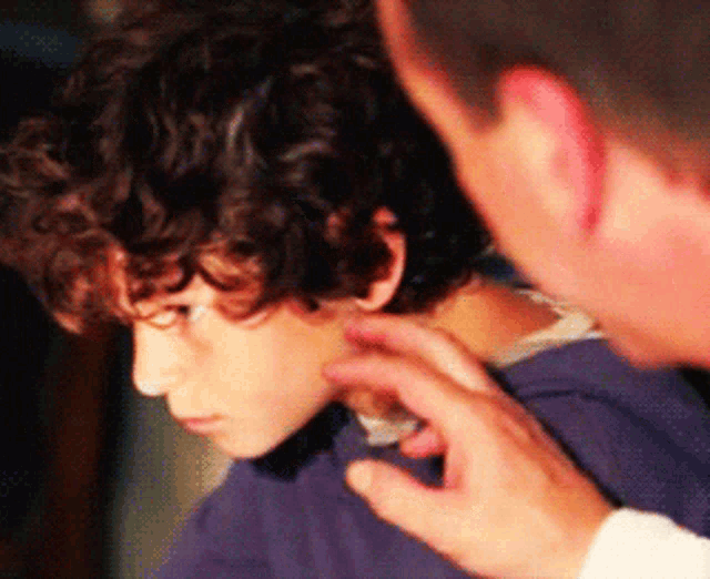 a man is touching a young boy 's neck with his hand