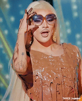 a drag queen wearing sunglasses and a brown dress