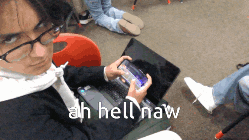 a man sitting in front of a laptop with ah hell naw written below him