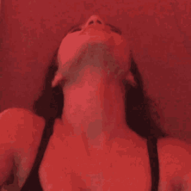 a close up of a woman 's face with a red background and a red light behind her .