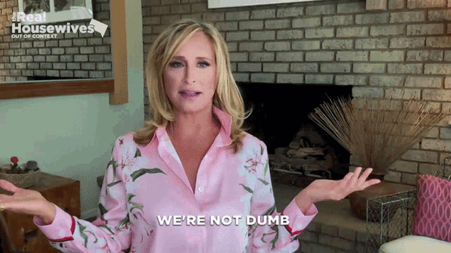 a woman says we 're not dumb in front of a brick fireplace