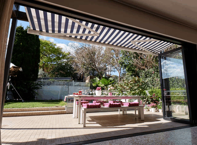 a striped awning is covering a patio area with a table and benches